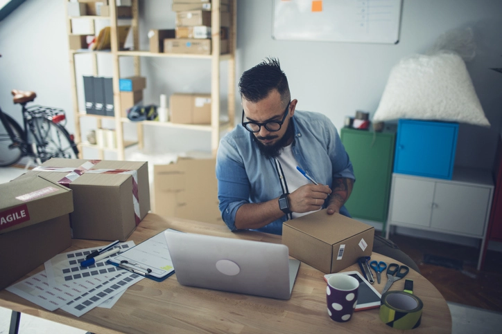 Bearded man adding notes on packages.