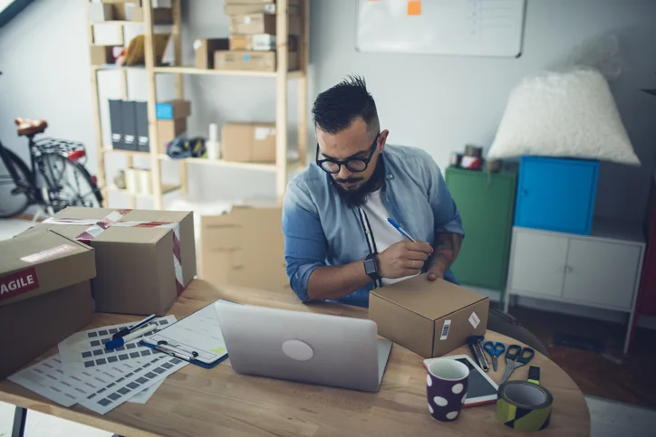 Bearded man adding notes on packages.