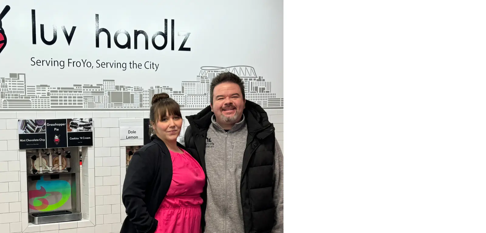 Man and woman stand in front of wall with Luv Handlz branding and frozen yogurt pumps